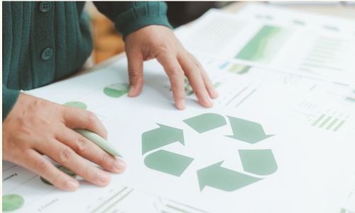 Une personne qui pose ses mains sur une feuille sur laque est dessiné des symboles d'eco conception et d'économie circulaire